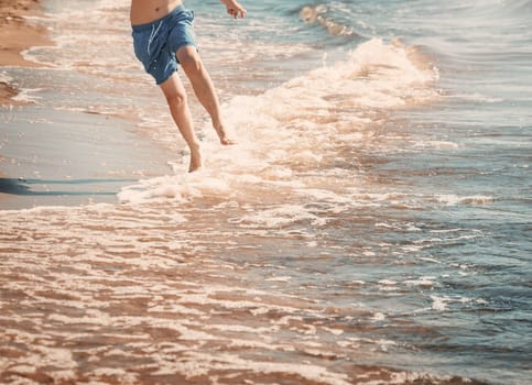 boy barefoot is jumping on the beach in water. Child is on vacation in summer at the sea