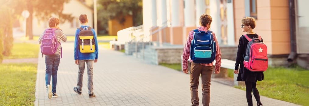 Children with rucksacks standing in the park near school. Pupils with books and backpacks outdoors