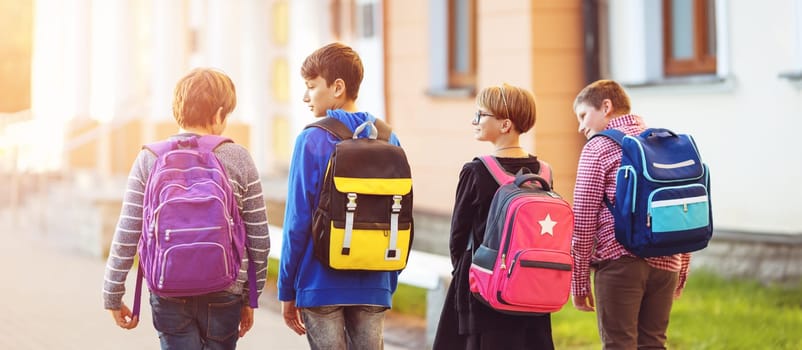Children with rucksacks standing in the park near school. Pupils with books and backpacks outdoors
