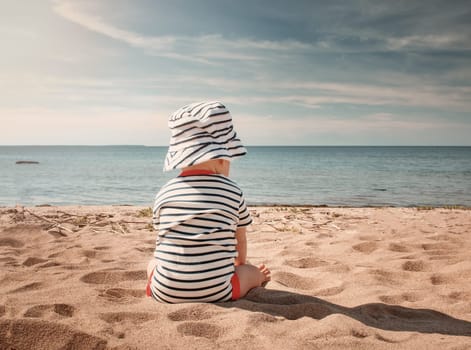 Nine month old baby boy sitting on the beach in beautiful summer day