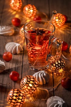Spicy winter tea or punch with anise and meringue pastry with Christmas lights
