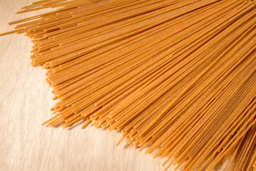 Wholewheat Spaghetti lies spread out on a wooden table.