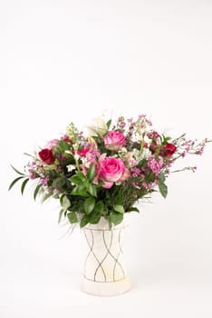 A beautiful flower arrangement in a vase set on a white islolated background.