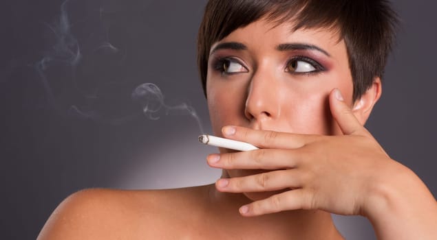 Smoke rises from cigarette hele by young female