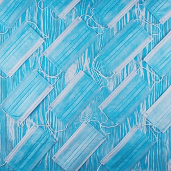 Medical masks on the blue colored background for protection from coronavirus. Epidemic and healthcare concept, pattern, flat lay.