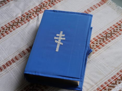 bible book in a blue cover with an embroidered silver cross on a table covered with a tablecloth