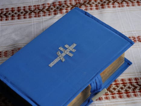 bible book in a blue cover with an embroidered silver cross on a table
