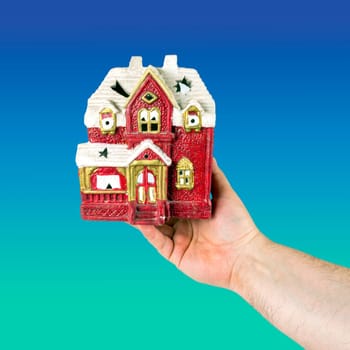 Hand holds toy house of red color. Concept of sale, purchase, rental or home insurance. Place for an inscription