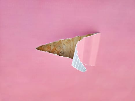A sheet of corrugated paper, a piece in the middle is torn off and the edge is bent. An angry blue paper is visible in the hole. A piece of paper.
