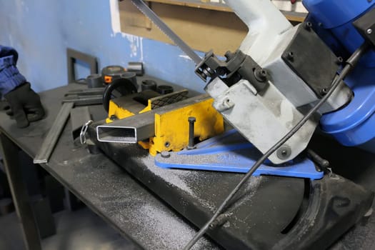 band saw cutting tool steel bar by automatic feed. Iron disc. Worker cuts off a piece of iron profile