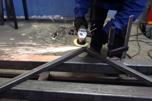 Grinding metal.Grinding wheel. Locksmith cleans iron corner after welding in workshop. Sparks are flying.