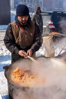 Hot pilaf in an iron vat. Rice meat and carrots. Steam is coming. Pilaf interfere with a spoon.