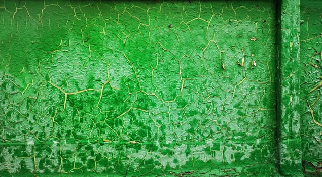 Old green paint is cracked. Background texture closeup.