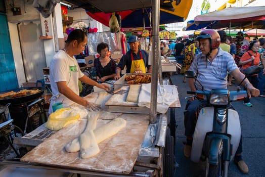 Georgetown, Penang/Malaysia - Jul 30 2016: A man ride motor to buy deep fried dough stall in morning market.