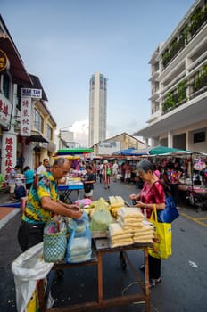 Georgetown, Penang/Malaysia - Aug 07 2016: Woman buy food at the morning market. Back is KOMTAR building.