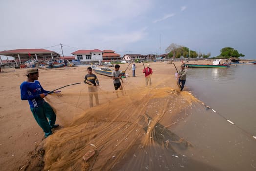 Kuala Muda, Penang/Malaysia - Mar 19 2017: Fisherman clean fishing net near beach.