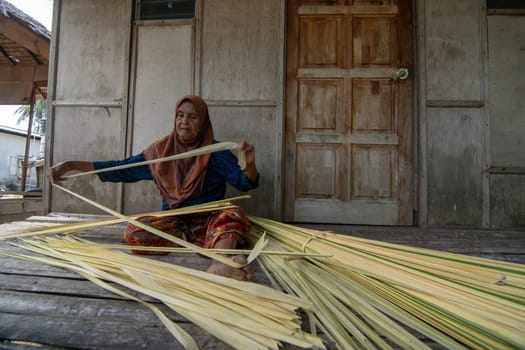 Kelantan/Malaysia - Jul 15 2017: A woman make traditional cigarette from Nipah leaf.