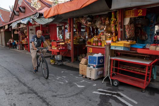 George Town, Penang/Malaysia - Jul 19 2018: An old man cycle near the stall sell joss stick ,joss paper at Goddess of Mercy temple.
