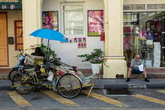 George Town, Penang/Malaysia - Jul 19 2018: Street life of Trishaw driver and people read newspaper at street.