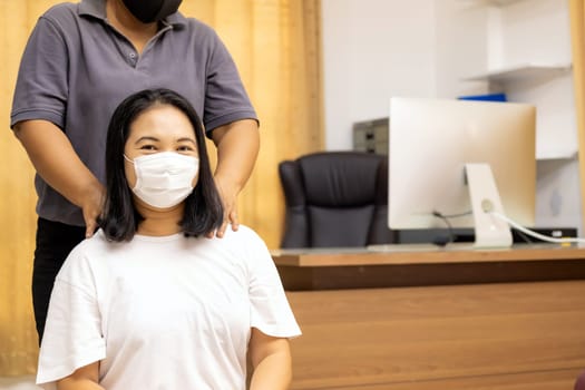 Quarantine asian woman do massage at home with face mask while city lockdown for social distance due to coronavirus pandemic. Massage is one of service business that shutdown while city lockdown.