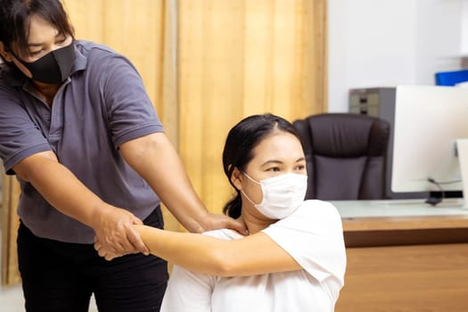 Quarantine asian woman do massage at home with face mask while city lockdown for social distance due to coronavirus pandemic. Massage is one of service business that shutdown while city lockdown.