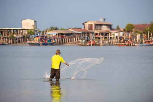 Sekinchan, Selangor/Malaysia - Oct 06 2019: A fisherman throw the net. Background is fishing village.