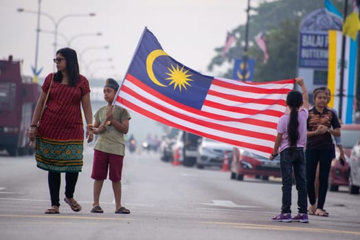Butterworth, Penang/Malaysia - Aug 31 2019: A Malaysian family hold the flag at street during Merdeka celebration.