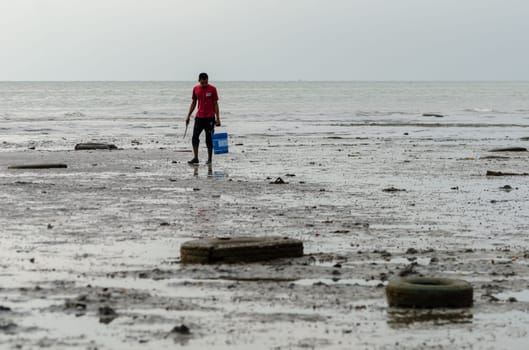 Batu Maung, Penang/Malaysia - Dec 28 2019: A fisherman search for clam.