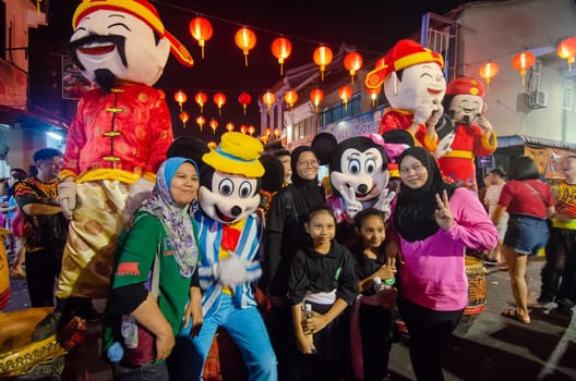 Georgetown, Penang/Malaysia - Jan 24 2020: Chinese new year god of prosperity and mickey mouse with Muslim tourist.