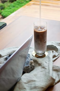 Glass of milk coffee and laptop on the table, stock photo