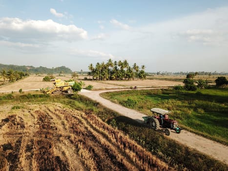 Pulau Sayak, Kedah/Malaysia - Feb 26 2020: Tractor move at path in paddy field.Harvester park at background.