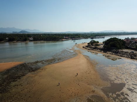 Two local walk at the muddy land near seashore during low tide season.