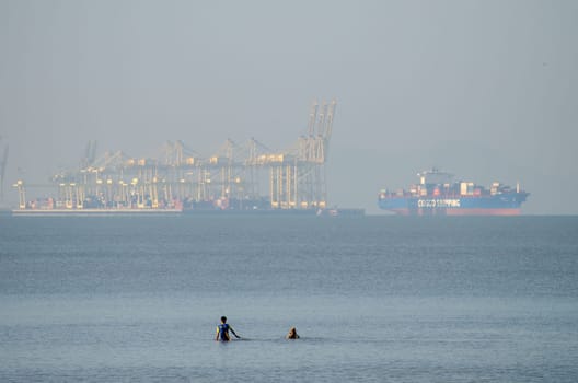 Penaga, Penang/Malaysia - Mar 14 2020: Two man fishing at sea. Background is container terminal at Butterworth.