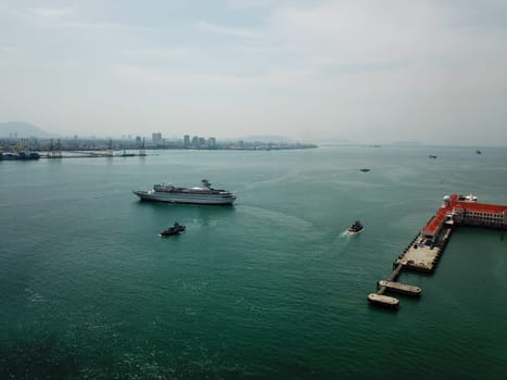 Georgetown, Penang/Malaysia - Mar 17 2020: Drone view tug boat assist cruise ship to departure.