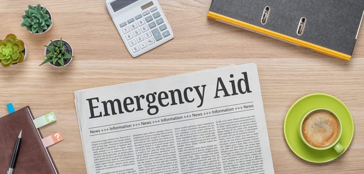 A newspaper on a desk with the headline Emergency Aid