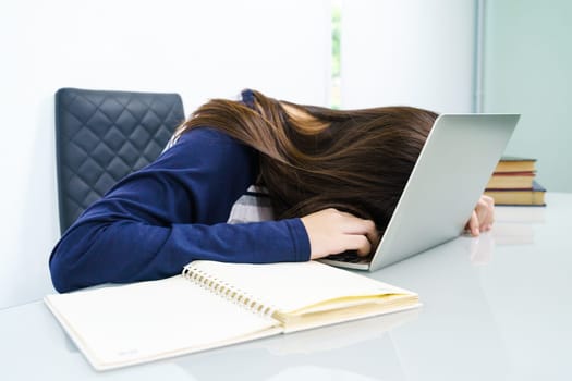 Young woman long hair tired from studying online and fall asleep on desk with laptop