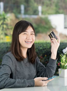 Young woman sitting showing credit card and holding smartphone for online shopping,Online shopping concept