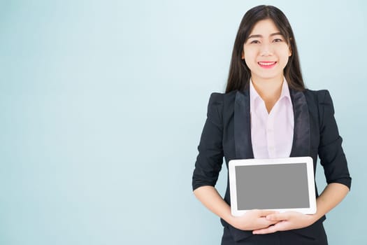 Young women in suit holding her digital tablet standing against blue background