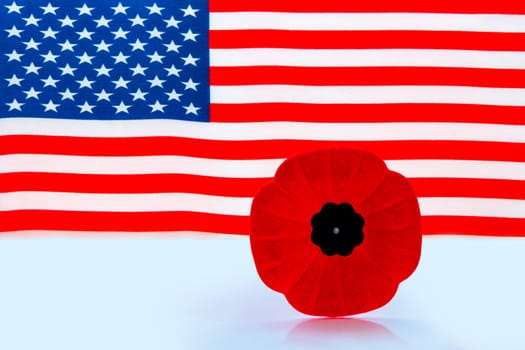 A remembrance day poppy flower with a American Flag on the background.