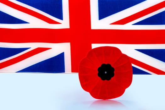 A remembrance day poppy flower with a UK Flag on the background.