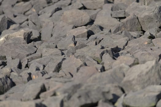 Lit by evening sunlight, A variety of sharply shaped stone boulders form a full frame abstract background texture image. Outdoors water protection
