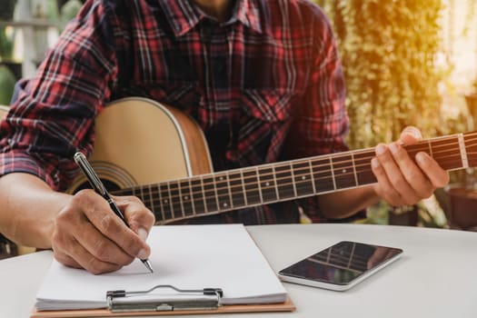 A Song writer holding pen for compose a song. Musician playing acoustic guitar. Live music and abstract musical concept.