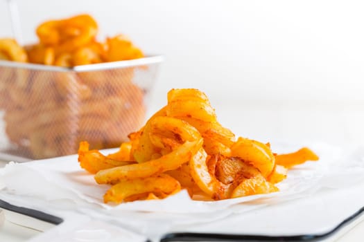 Spicy seasoned curly fries. Ready to eat on white background