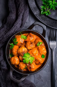 Meatballs with tomato sauce in black pan..