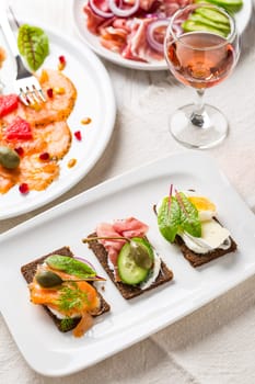 Variation of healthy open sandwiches on Pumpernickel bread with vegetables, salmon, ham and appetizers with red wine