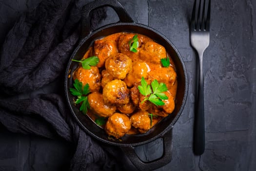 Meatballs with tomato sauce in black pan..
