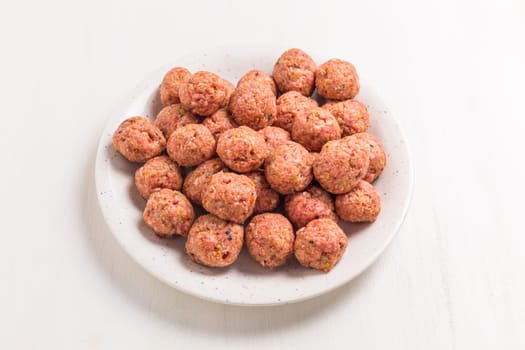 Raw meatballs on plate, ready for cooking or baking on white background