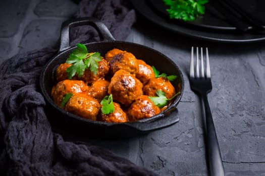 Meatballs with tomato sauce in black pan..