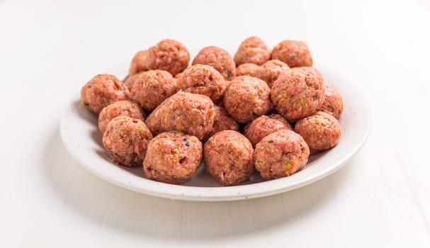 Raw meatballs on plate, ready for cooking or baking on white background