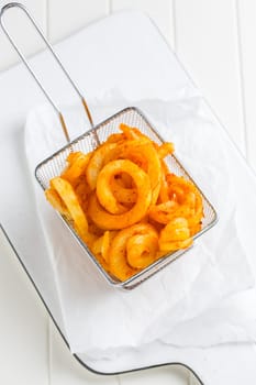 Spicy seasoned curly fries. Ready to eat on white background